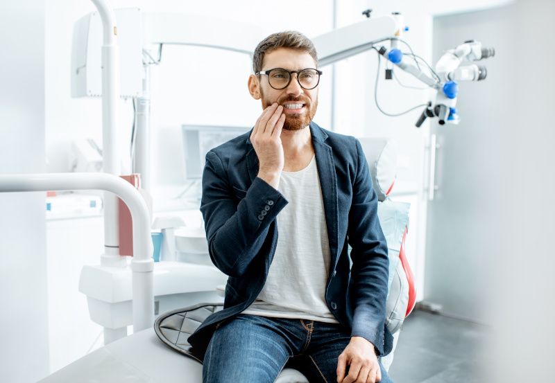 Mann mit Zahnschmerzen sitzt auf einem Zahnarztstuhl