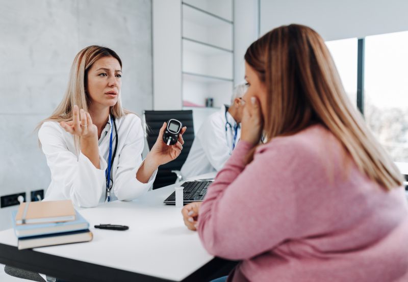 Ärztin spricht mit Patientin über Blutzuckerwert
