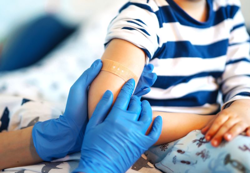 Bub mit Pflaster auf dem Arm nach einer Impfung