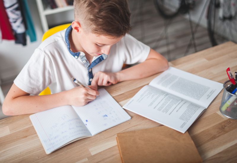Bub sitzt bei Schreibtisch und lernt