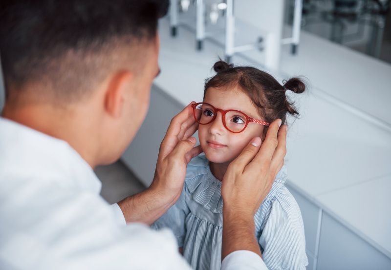 Augenarzt setzt kleinem Mädchen eine Brille auf