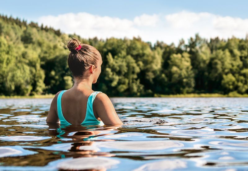 Frau schwimmt im Sommer in einem See