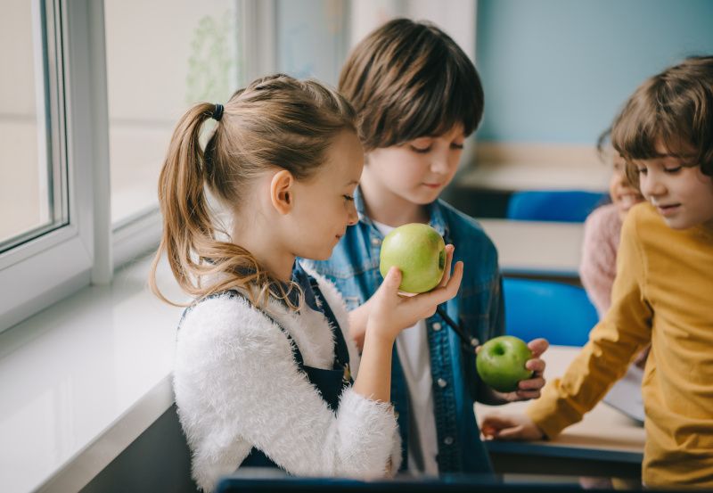 Schulkinder essen Äpfel im Klassenraum 