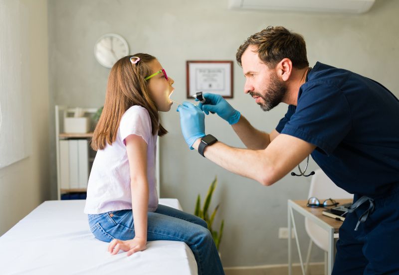 HNO-Arzt untersucht Rachen eines Mädchens