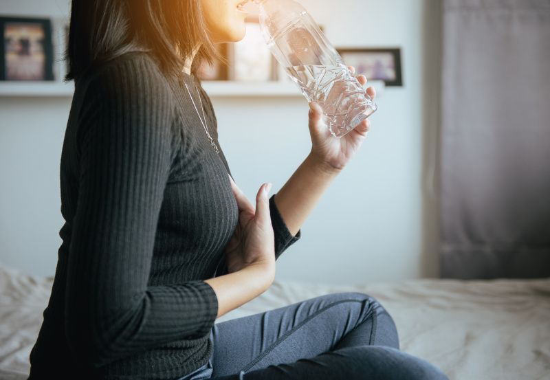 Frau mit Reflux trinkt aus einer Wasserflasche