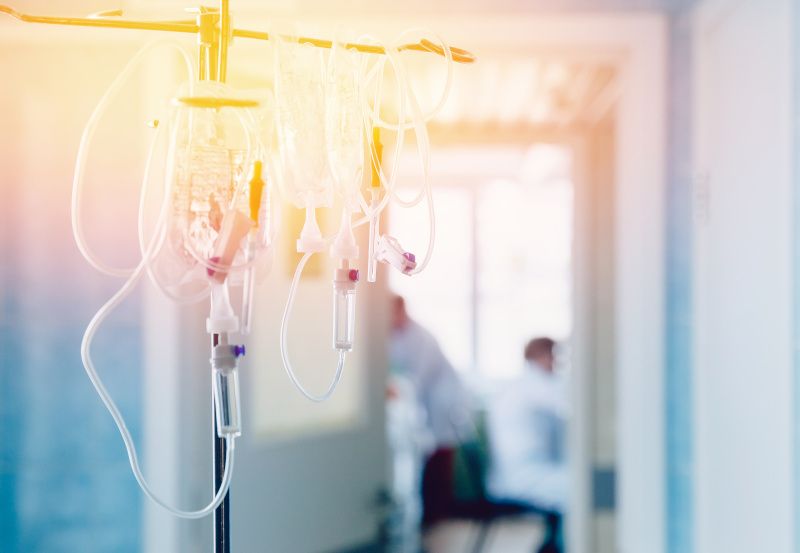Infusionsflasche, im Hintergrund Ärzte