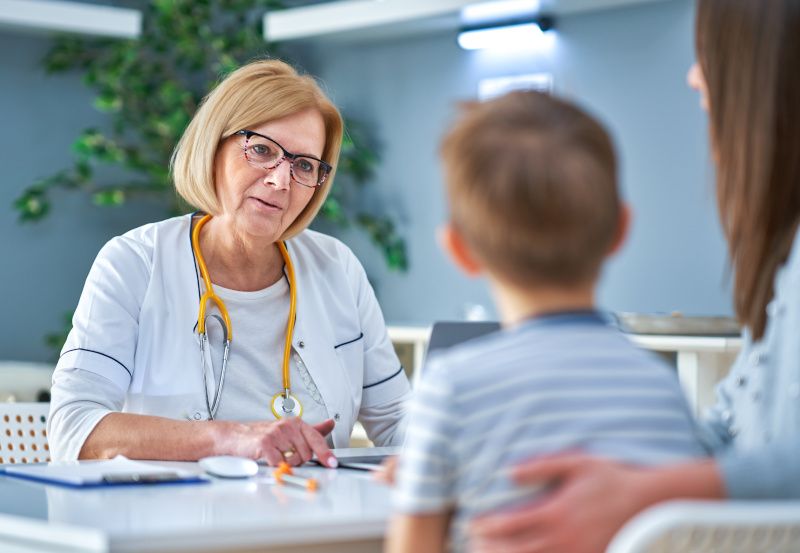 Ärztin spricht mit kleinem Bub und dessen Mutter
