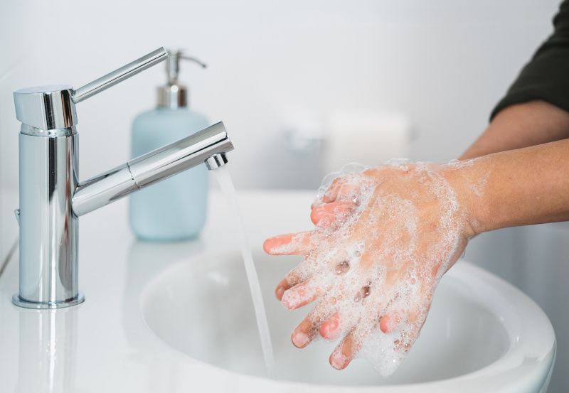 Hände einer Frau beim Händewaschen mit Seife