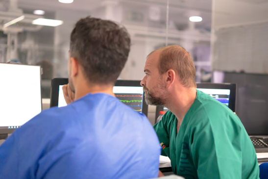 Techniker und Arzt vor einem Computer auf der Intensivstation