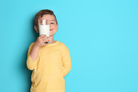 Bub mit einem Glas Milch vor blauem Hintergrund