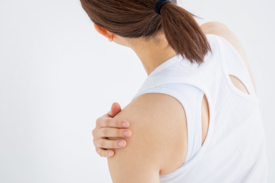 Frau hält ihre Schulter fest