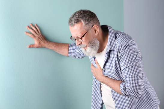 Mann hat Brustschmerzen und hält sich an einer Wand an