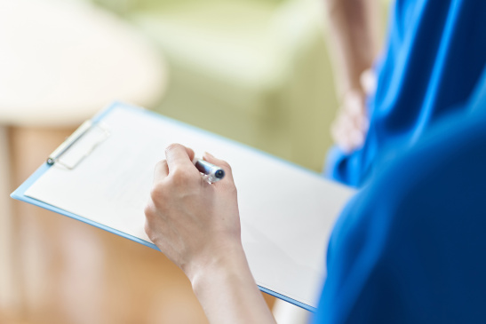 Hand eines Krankenpflegers mit Stift und Clipboard