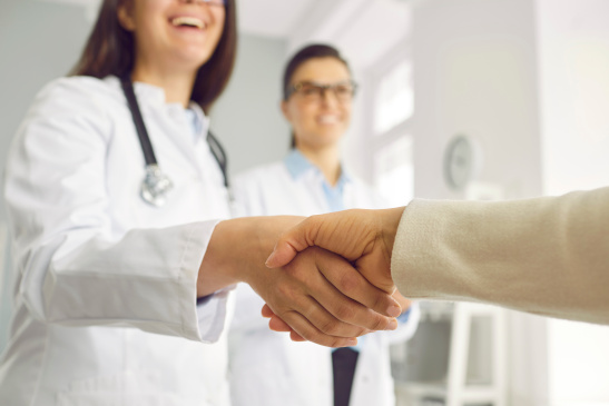 Fröhliche Ärztin schüttelt jemandem die Hand