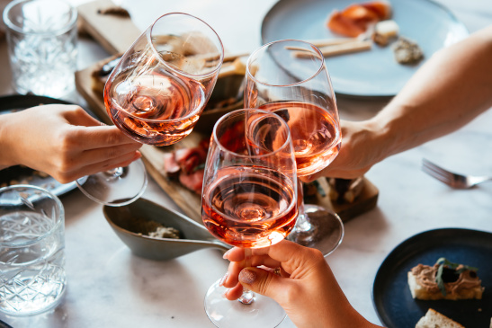 Drei Personen stoßen beim Essen mit Wein an