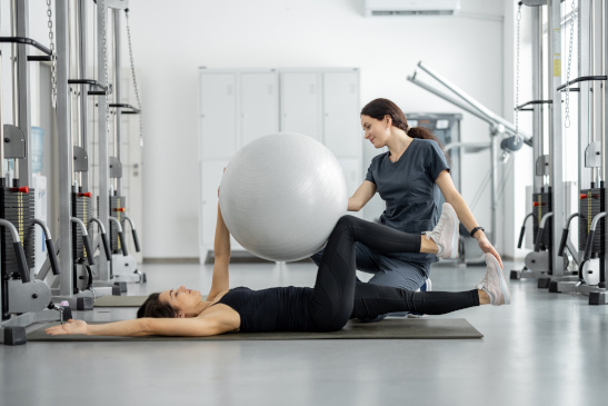 Therapeutin trainiert mit Frau in einem Fitnessstudio