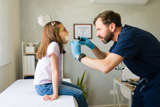 HNO-Arzt untersucht Rachen eines Mädchens