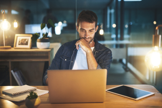 Mann sitzt spätabends vor dem Laptop und arbeitet