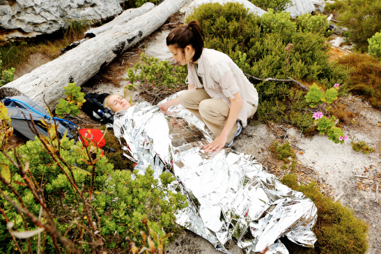 Frau deckt Freundin mit Notfall Decke zu