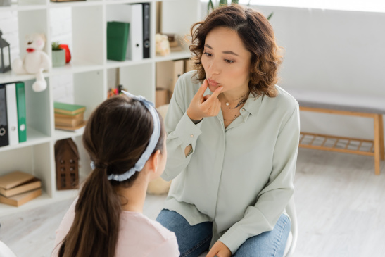 Logopädin macht Sprechübungen mit Kind
