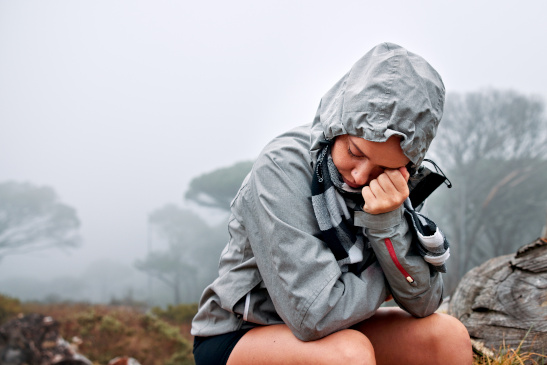 Junge Frau sitzt auf einem Baumstamm und wartet auf Hilfe