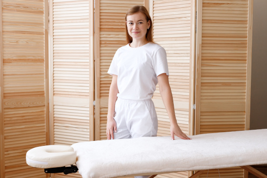 Masseurin steht neben einer Behandlungsliege