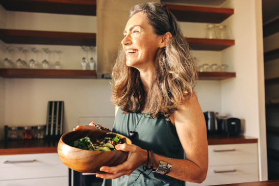Fröhliche Frau hält Salatschüssel in Händen