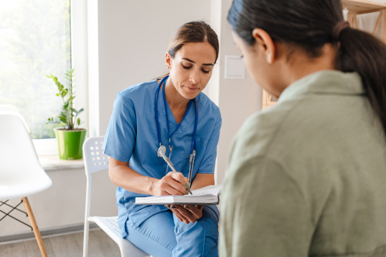 Ärztin spricht mit Frau und macht sich Notizen