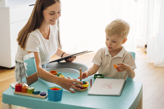 Ergotherapeutin macht Übungen mit kleinem Bub