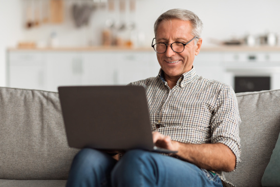 Mann sitzt mit Laptop auf der Couch